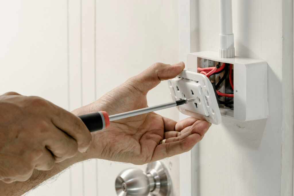 An electrician is installing a new wall outlet.