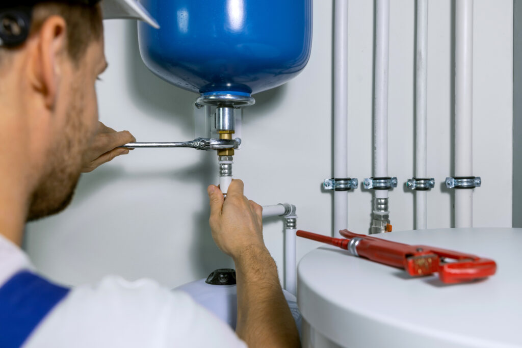 A plumber installing an expansion tank for a house heating system.